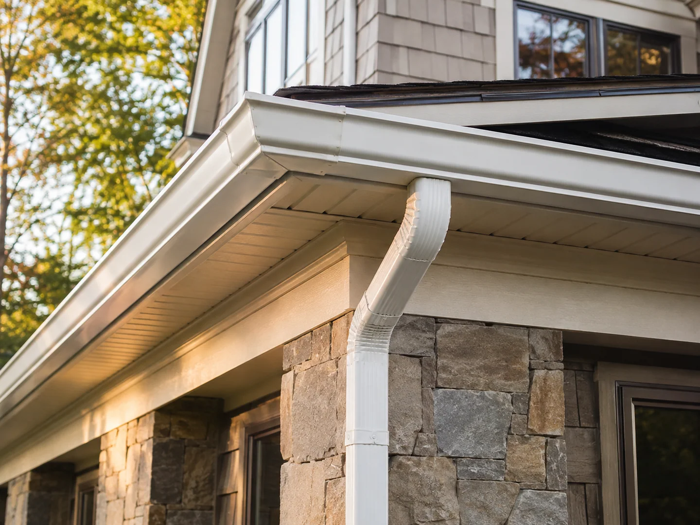 Finished seamless gutter corner and downspout connection on a stone home