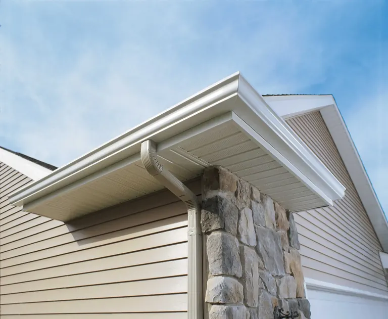 White gutter and downspout on a stone-trimmed home